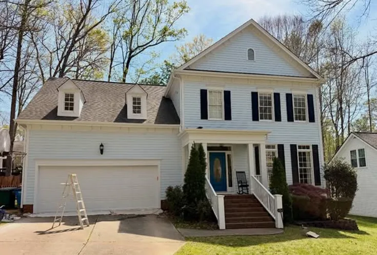 The same colonial repainted crisp white with navy shutters and a teal front door